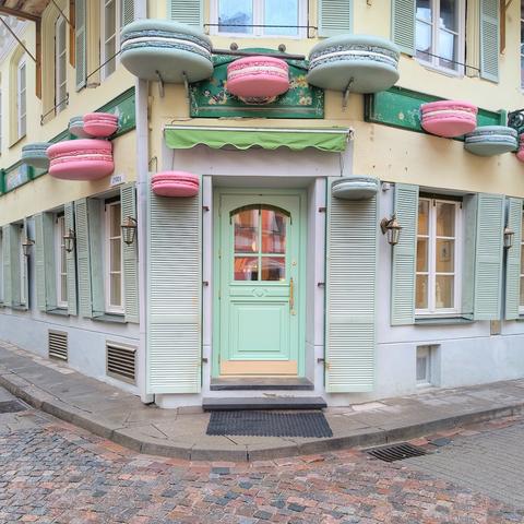 Seafoam green door on a corner. The door and facade is dotted with giant pastel macarons.
