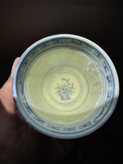 A blue and white rice grain pattern porcelain cup with green tea.