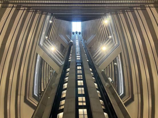 Three elevators descend from the skylight to ground level. The lines are balconies that form angles around the shaft.