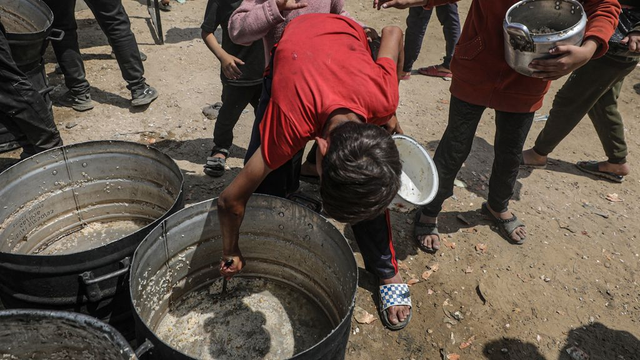 Een jongen schraapt de laatste resten uit een pan bij een gaarkeuken in Noord-Gaza (foto EPA)