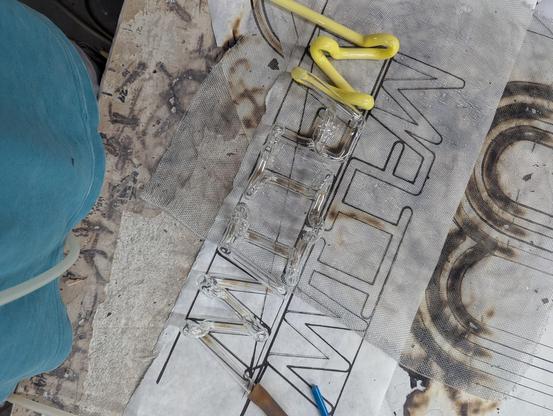 A clear WIIF with yellow M bent in glass tube on its paper pattern with screen