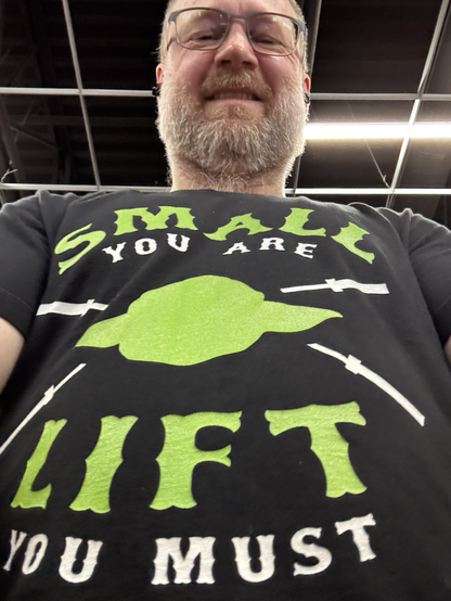 Wearing T-shirt with yoda head crossed with empty barbells with the words “small you are; lift you must”.