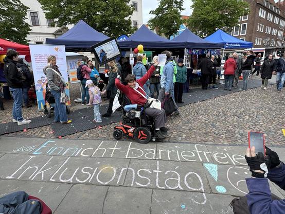 Kreidespruch auf dem Marktplatz mit vielen Menschen: Ein nicht barrierefrteier Inklusionsstag! und smiley der unzufreiden ist