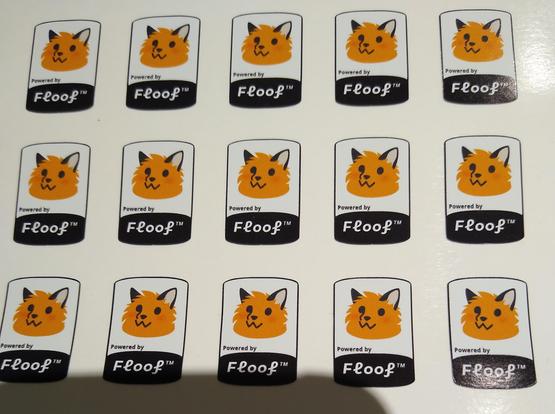 A WHOLE BUNCH of laptop sized stickers of a blobfox and "powered by floof" text in a grouping closeup.