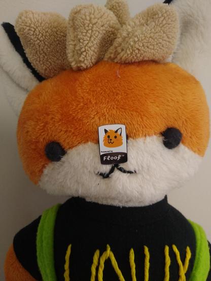 Xenia the linux fox plush with a sticker on her nose, to certify that she is powered by floof.