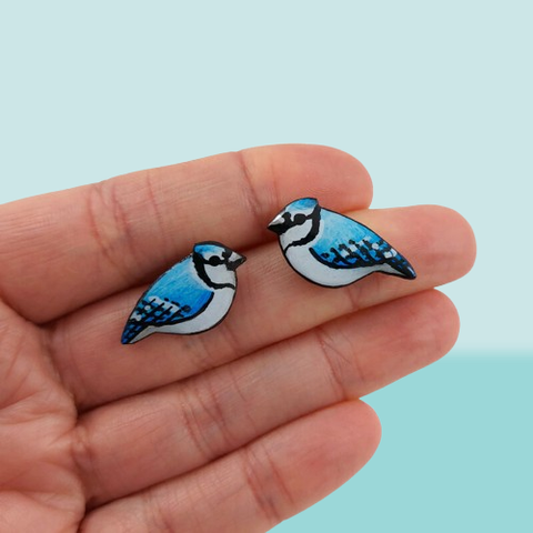 Puces d'oreilles fantaisie éco-responsables en forme de petits geais bleus.
Les perles sont réalisées en CD recyclé, découpées et peintes à la main, puis recouvertes de résine époxy.
Les tiges sont en acier inoxydable.