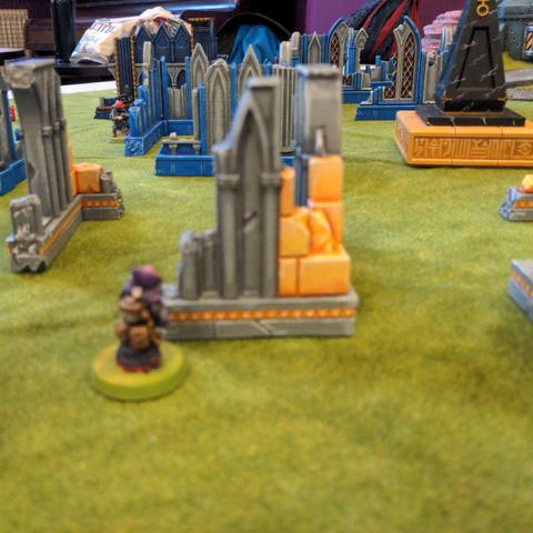 A genestealer cultist spots an imperial guardsman poor choice of helmet colour (bright red) through the vibrant ruins.