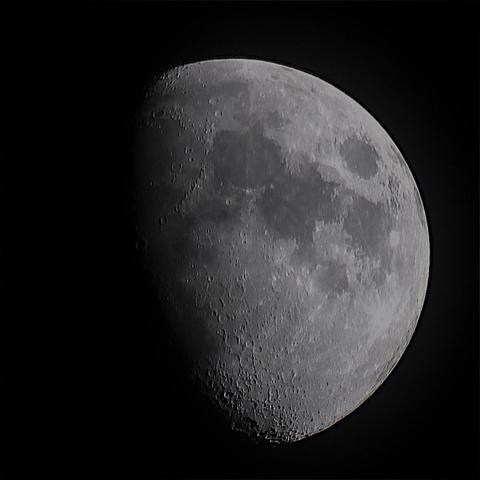 The Moon at waxing gibbous phase seen through thin cloud on a dark background.