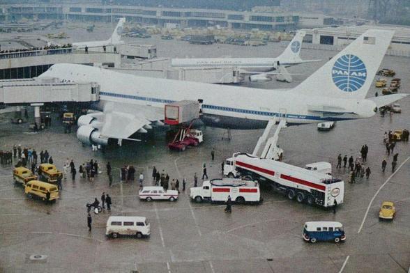 The large 747 is parked at a gate receiving a lot of attention.