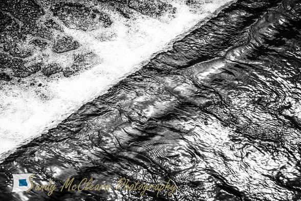 Sun reflects off water flowing over a weir.