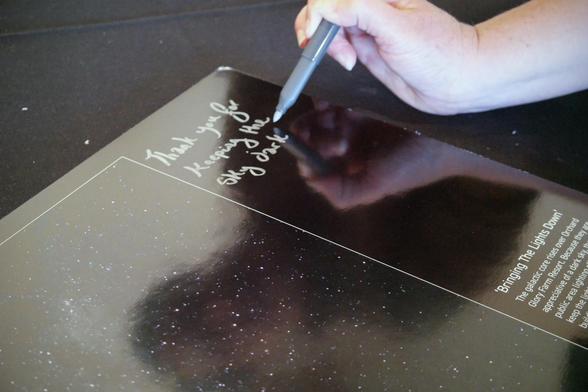 Corner of the photograph in the process of being signed.