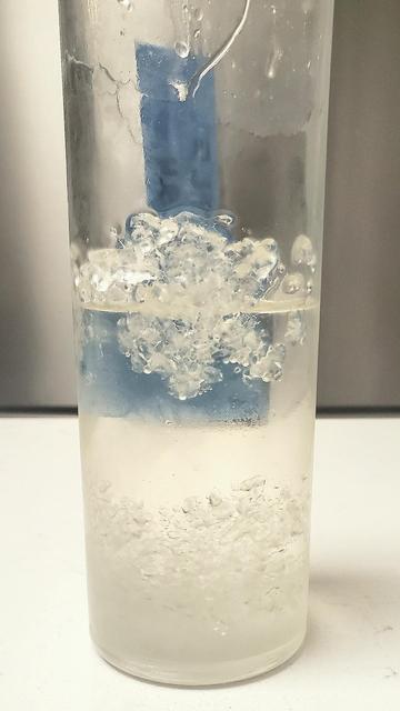 Picture of a bottle of homemade simple syrup. In the bottle, some of the sugar has crystallized out of the liquid onto the sides of the bottle.
