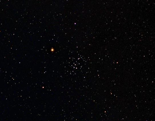 The Beehive cluster of stars at centre. Bright planet Mars to its left. Other fainter star dots on a dark background.