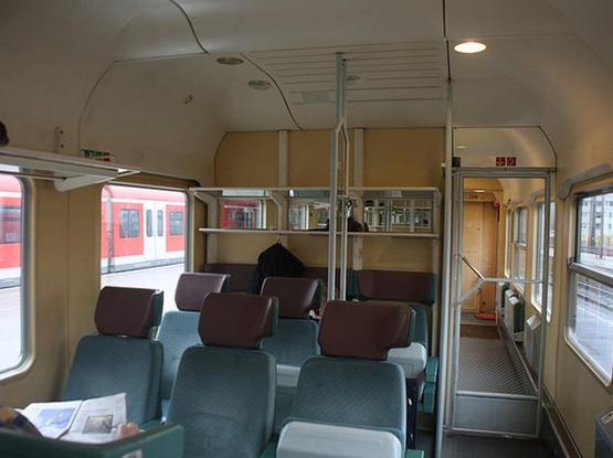 Foto vom Interieur eines Interregio-Waggons aus den 1990er Jahren mit türkisfarbenen Sitzen.