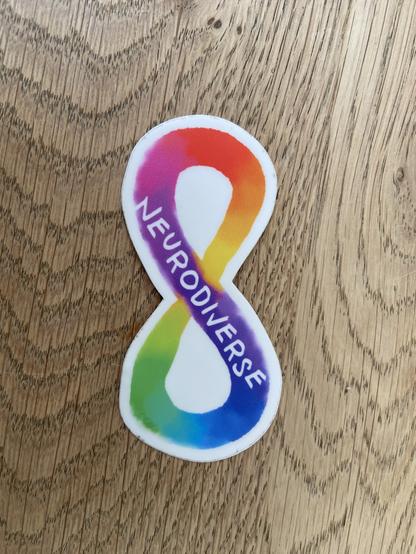 Een sticker in de vorm van een lemniscaat met regenboog gradient en de tekst neurodiverse