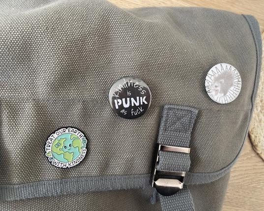 Een grijze tas met twee nieuwe buttons er op en ook nog eentje van de aarde.