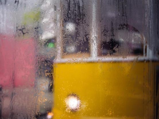 A yellow tram viewed through condensation-covered glass.