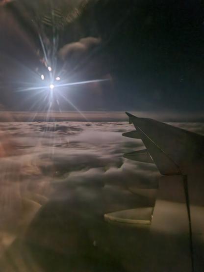 Blick durch das Fenster eines Flugzeugs auf die Sonne über den Wolken