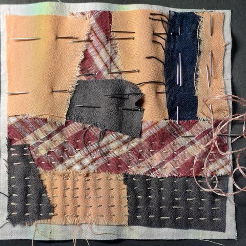 Ein paar Stoffschnipsel, die für eine Stoffcollage auf ein Stück Untergrundstoff geheftet sind und aufgenäht werden.