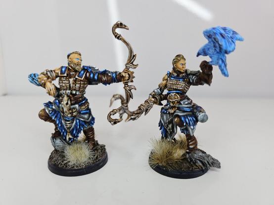 To incredibly well highlighted archers, one with the bow post shot aan the other Holding up a blue Falcon.