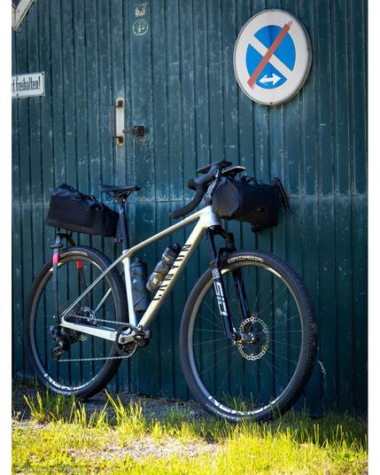 A Canyon Exceed with drop bars and Tailfin bikepacking packs front (Drop Bar Bag Small) and rear (Aeropack Cargo) in front of an old barn door.