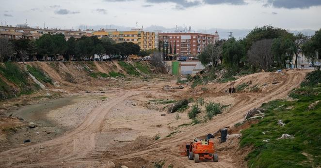 Das Foto zeigt die Zerstörungen im spanischen Paiporta. In einem eigentlich trockenen Flussbett ist die braune Erde zu sehen. Am Bildrand ein Bagger.