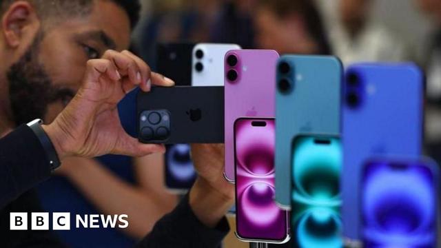 Man looking at iphones that are on display in a range of blue green and purple colours