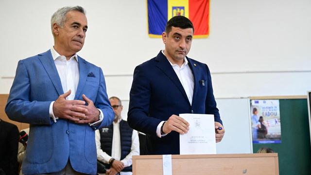 Simion, der Kanidat der rechtsnationalen AUR-Partei wirft seinen Stimmzettel in eine Wahlurne. Neben ihm steht der disqualifizierte Kandidat Georgescu.