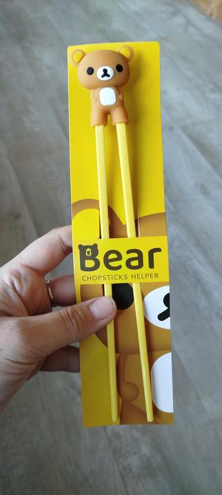 Ein paar gelbe Plastik Essstäbchen, oben zusammengesteckt mit einem Bärchen aus Silikon