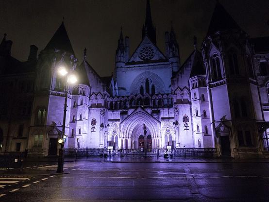 A nighttime photograph of the Royal Courts of Justice in London, UK
