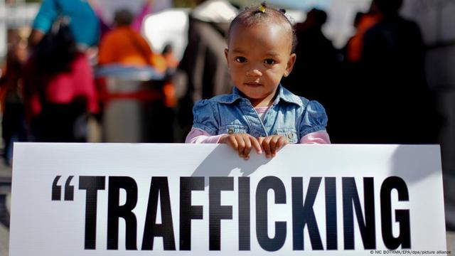 A little girl holding up a poster of a sign that reads "Trafficking"