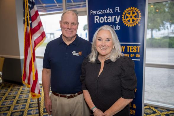 Kevin Green and Dr. Martha D. Saunders pose in front of an American flag and a banner that reads, "Pensacola, FL Rotary Club."
