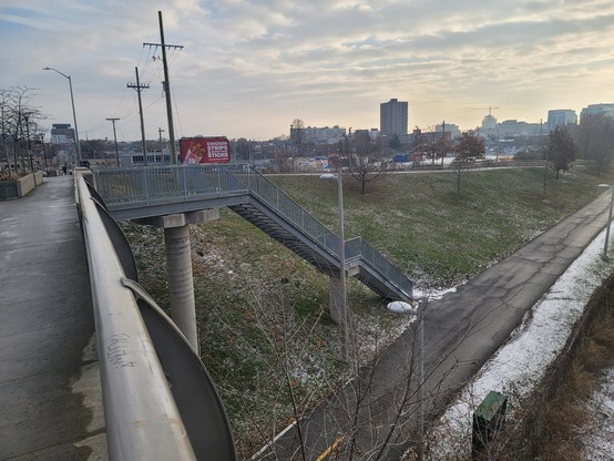 Metal stairway coming down perpendicular from a bridge to a multi use pathway