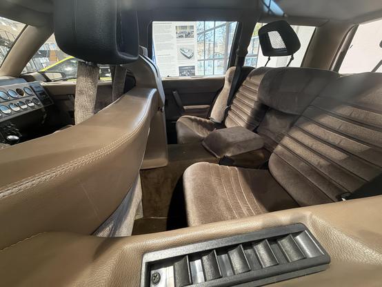 Plush brown leather seats in the rear of a 1970s sedan, with massive centre column