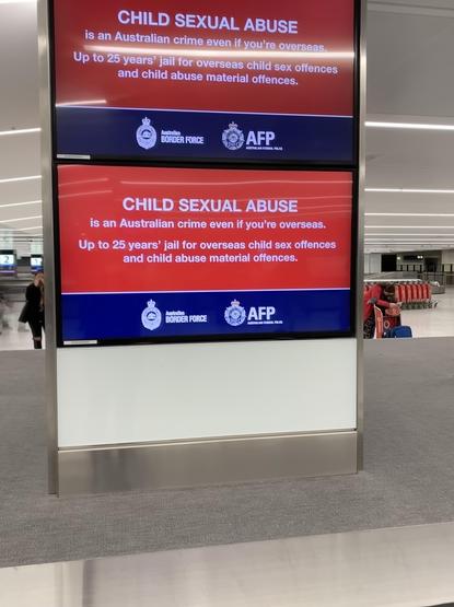 An electronic sign at an airport baggage claim, which states on a bold red background:

CHILD SEXUAL ABUSE
is an Australian crime even if you're overseas.
Up to 25 years' jail for overseas child sex offences and child abuse material offences.

(logo for Australian Border Force)
(logo for AFP, Australian Federal Police)