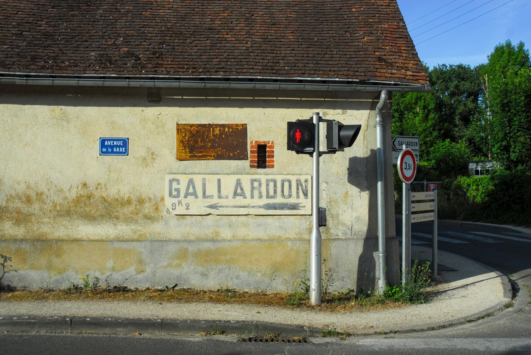 An old sign pointing towards Gallardon painted on an equally old housr.