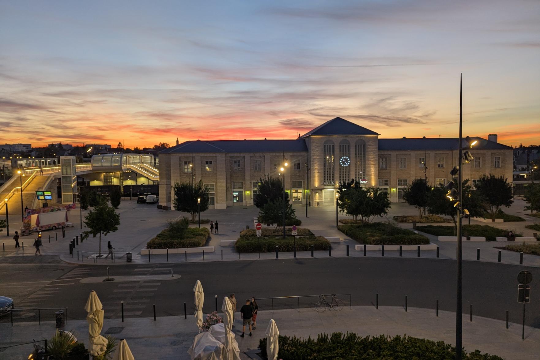 View across the station square after sunset to the station building. Orange colours in the sky.