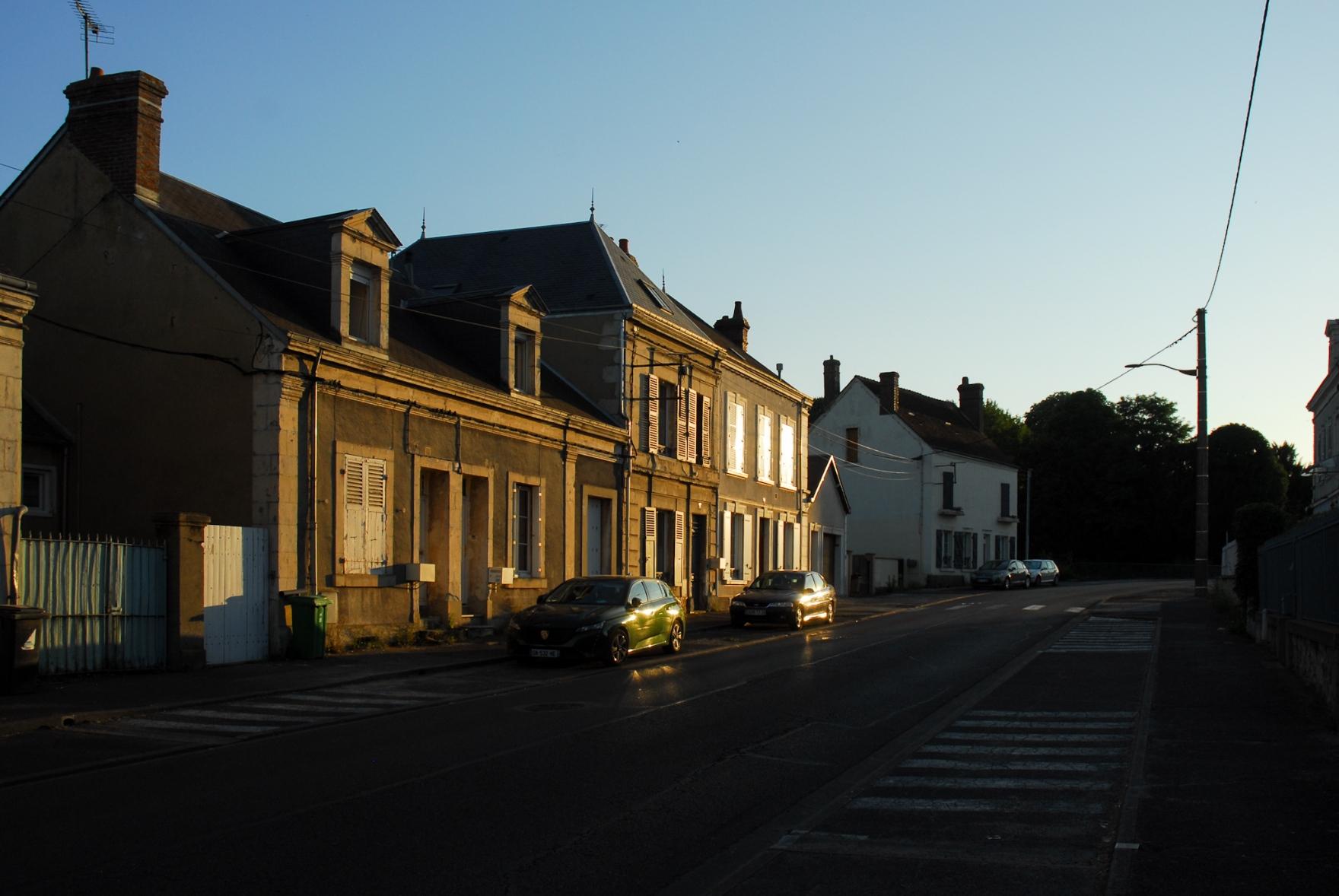 The last bit of evening sunlight reflecting on old houses along a street