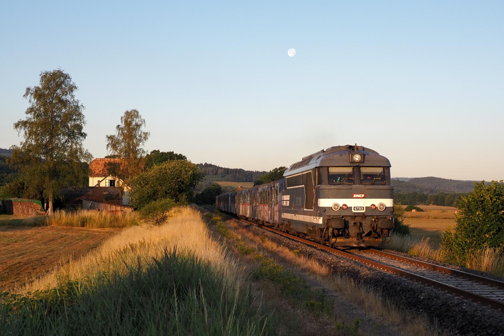 The last diesel loco hauled train of France in the soft first light of a new day in a tranquil landscape with fields and forests
