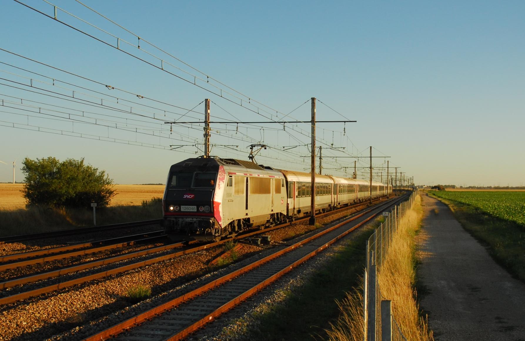 A Sybic loco with a Corail Intercités train on a main line in the very warm light of a summer evening