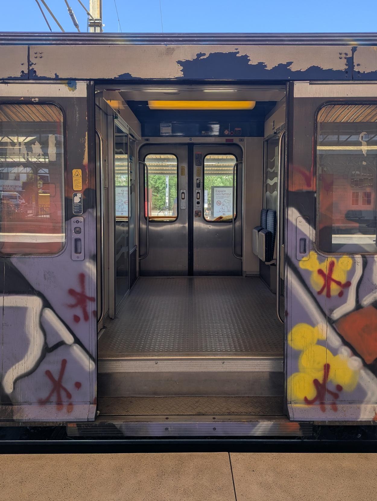View through the open doors of a badly graffitied RRR unit into the vestibule.