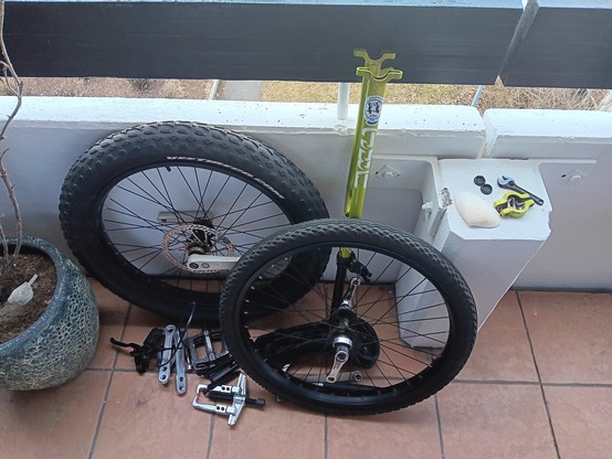 Disassembled unicycle with an extra wheel.
