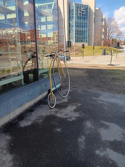 Penny farthing leaning against the glass window of a store. 