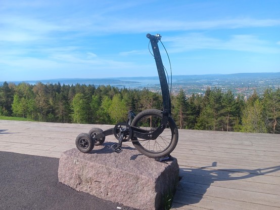 A HalfBike resting on a large stone with an outlook over the whole of Oslo. Taken from the top of Grefsenkollen.