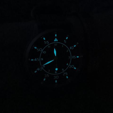 A night shot of a lumed watch face that is flieger type b style. 