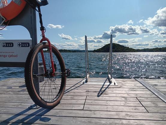 A unicycle next to open water on a boardwalk. 