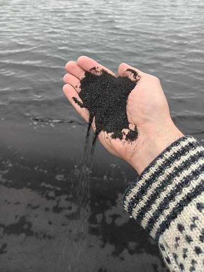 Black sand pouring from my hand. 