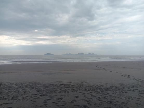 View from a black sand beach with moody skies looking out over the water towards Vestmannaeyjar