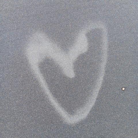 Dark gray sand with slightly lighter sand used to make a heart shape. 