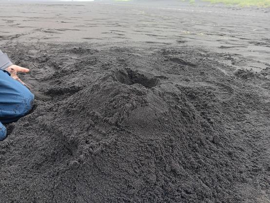 Sand castle, except it's a sand volcano. Made of very dark gray sand. 